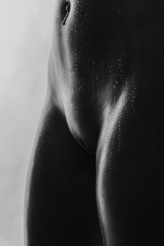 Eine sinnliche Schwarz-Weiß-Aufnahme eines Venushügels mit Wassertropfen, festgehalten von Daniel Fink-Fotografie aus Karlsruhe. Diese Ästhetik des Körpers verzaubert und zeigt die Vielfalt eines Studio Akt Shootings.
